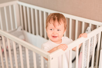 Cute little baby boy looking out of his bed