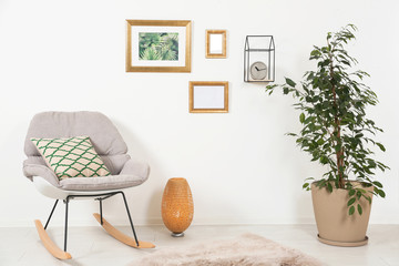 Stylish living room interior with ficus and rocking chair near white wall