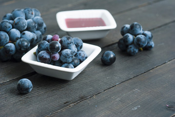 red grape juice in china bowl, black wood table background