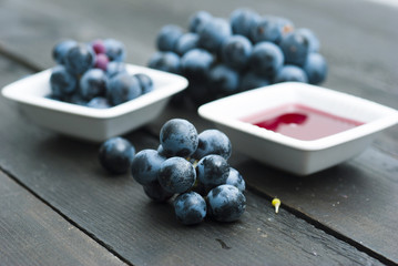 red grape juice in china bowl, black wood table background