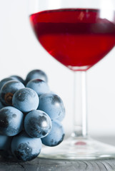 glass of red wine and grapes on black wood table background