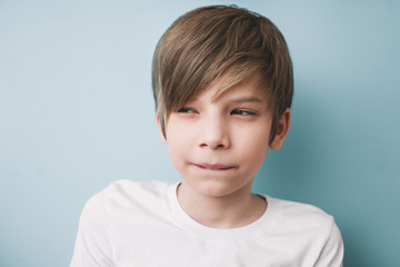Thoughtful boy with bitter prank bitten his lower lip with his teeth and narrowed his eyes