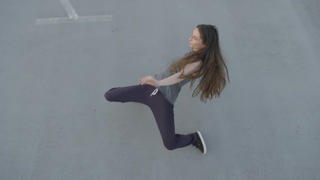 Top shot of a hip hop dancer, performing stylish moves on a concrete grey floor
