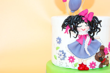 Obraz na płótnie Canvas A Cake With a Dolly with Long Black Hair and Baloons made with Sugar Paste on Orange Background