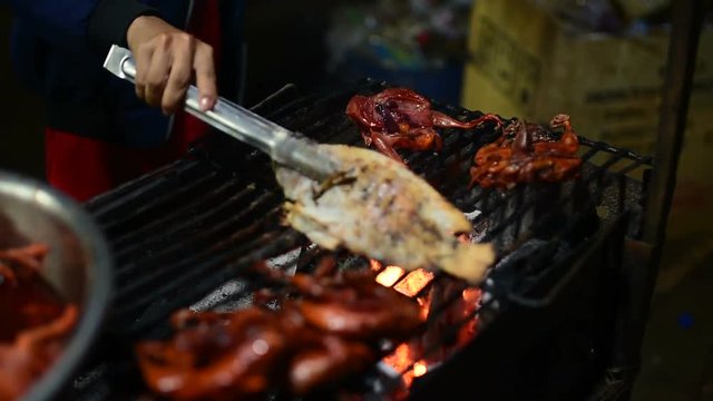 Chicken  and fish prepared by Cambodian woman to be grilled, Cambodian night street food market. Banlung town. 
