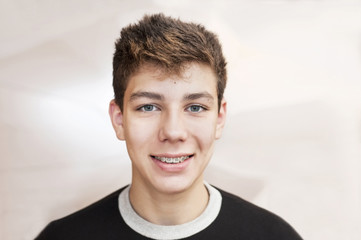 A boy smiles at the abstract background and his braces are clearly visible on his teeth