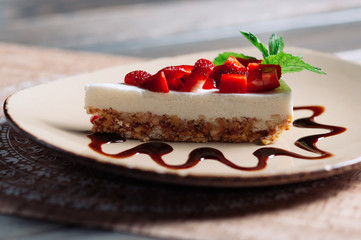 Slice of strawberry yogurt or coconut cake decorated with fresh fruits and mint on a plate. Delicious and sweet pink cake for Valentines or birthday party. Homemade bakery concept. Selective focus