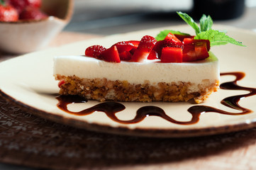 Slice of strawberry yogurt or coconut cake decorated with fresh fruits and mint on a plate. Delicious and sweet pink cake for Valentines or birthday party. Homemade bakery concept. Selective focus