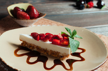 Slice of strawberry yogurt or coconut cake decorated with fresh fruits and mint on a plate. Delicious and sweet pink cake for Valentines or birthday party. Homemade bakery concept. Selective focus