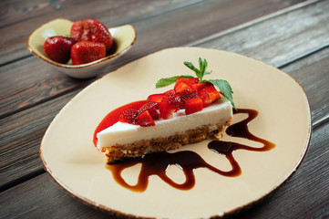 Slice of strawberry yogurt or coconut cake decorated with fresh fruits and mint on a plate. Delicious and sweet pink cake for Valentines or birthday party. Homemade bakery concept. Selective focus