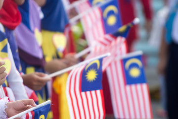 Hand waving Malaysia flag also known as Jalur Gemilang in conjunction with the Independence Day...