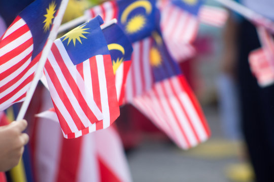 Hand Waving Malaysia Flag Also Known As Jalur Gemilang In Conjunction With The Independence Day Celebration Or Merdeka Day.