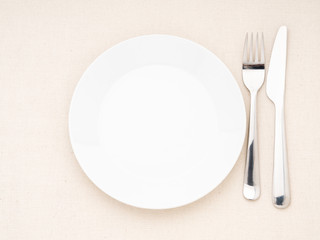 Blank flat plate, fork, knife on white table, top view. Mock up, copy space