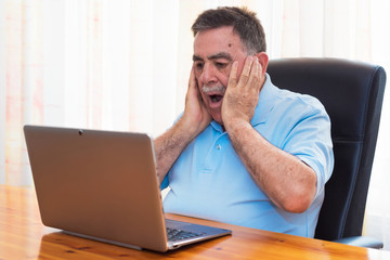 Surprised Senior man working with laptop.