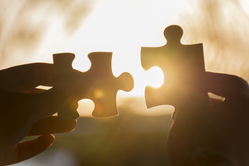 Silhouette hand trying to connect puzzle.