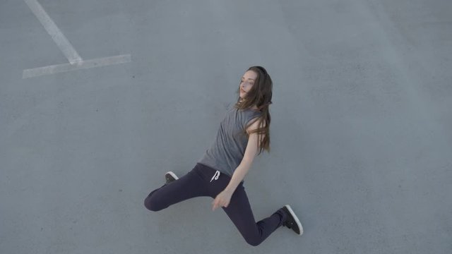 female dancer performing piroutte on a concrete grey floor