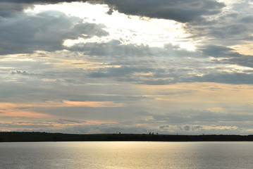 Sun between clouds reflecting in the lake