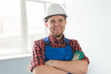 Close up of happy caucasian male builder with crossed hands wearing white helmet