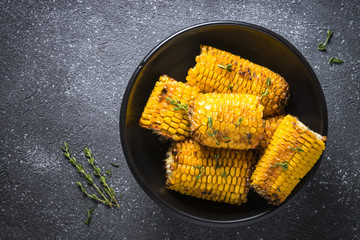 Grilled corn with spices top view on black.