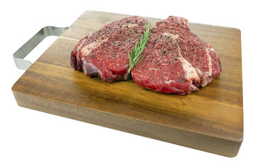 Fototapeta premium Peppered Raw Rib Eye Steaks on a Wooden Board Isolated