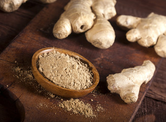 Ginger root and ginger powder on wooden background