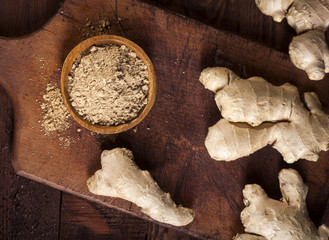 Ginger root and ginger powder on wooden background