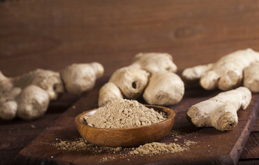 Ginger root and ginger powder on wooden background