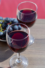 Two wine glasses with red wine served with red grape on outdoor terrace