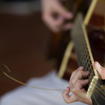 Closeup of musician's hands playing guitar at a concert.