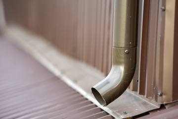 Close-up of brown new gutter metal system pipe on wall. Drain protection, professional work concept.