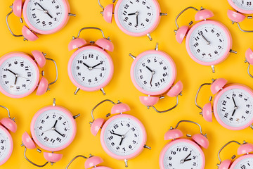 Pink alarm clock on yellow background.