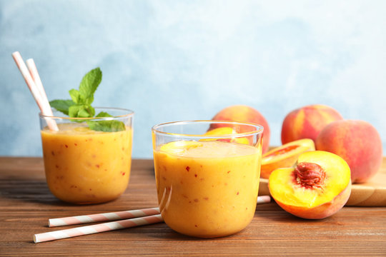 Tasty peach smoothie and fresh fruit on table
