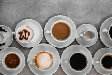 Cups of fresh aromatic coffee on grey background, top view