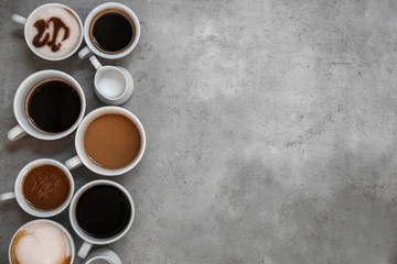 Cups of fresh aromatic coffee on grey background, top view