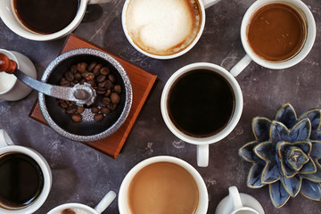 Cups of fresh aromatic coffee on grey background, top view