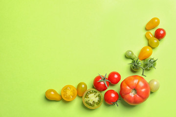 Flat lay composition with different tasty tomatoes and space for text on color background