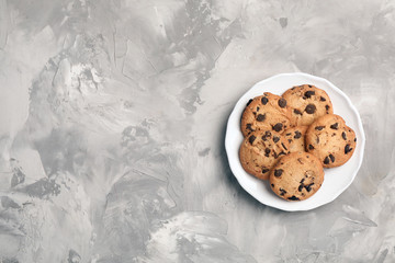 Plate with chocolate cookies and space for text on gray background, top view