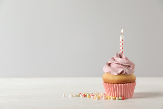 Delicious birthday cupcake with burning candle and space for text on light background