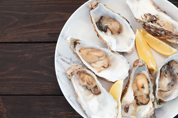 Fresh oysters with cut juicy lemon and space for text on table, top view