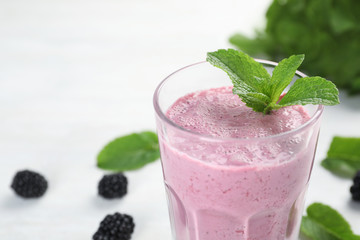 Glass with tasty blackberry yogurt smoothie on table, closeup