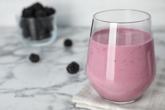 Glass with blackberry yogurt smoothie on marble table