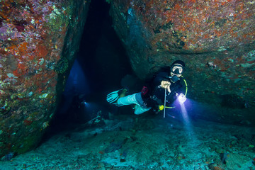 SCUBA diver exploring a deep, dark tropical coral reef