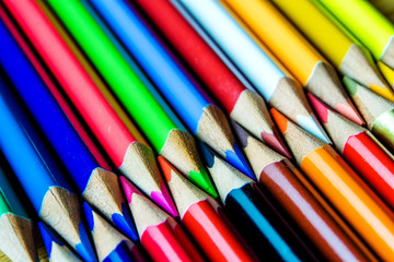 multicolored pencils on wooden background forming a pattern with copy space