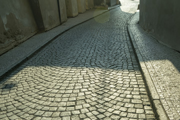 a deserted street paved of cobblestone and stone buildings in the morning, in the old town