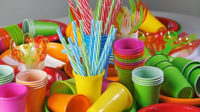 Colorful plastic disposable tableware for picnic on table. Rotation