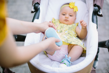 foreground of baby carriage and mothers hand at outdoor, spring or summer season with fresh green background