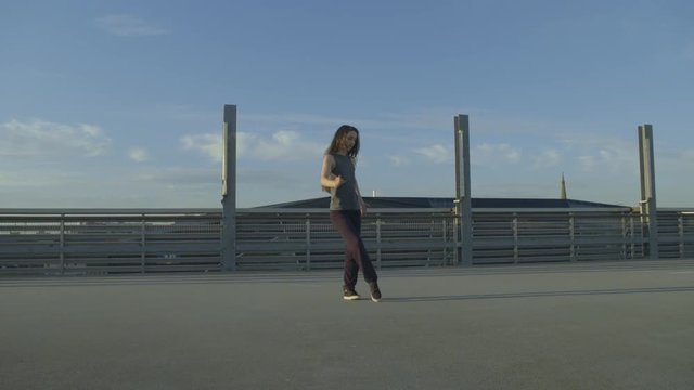 female Dancer walks into the frame, dancing hip hop on a concrete envoirenment 