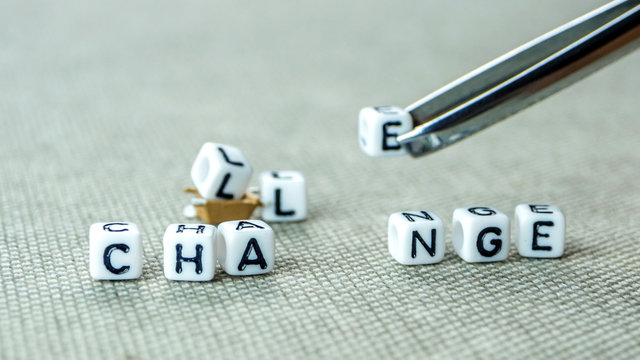 Removing white cubes with a tweezer with letters l and e of the word challenge creating new word change on grey background with miniature figurines