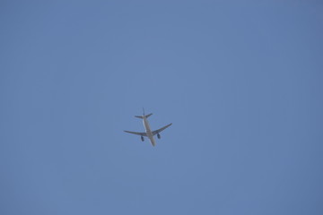 A airplane flies through the blue and cloudless sky.