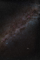 Center of milky way in night sky with red nebulas and andromeda galaxy